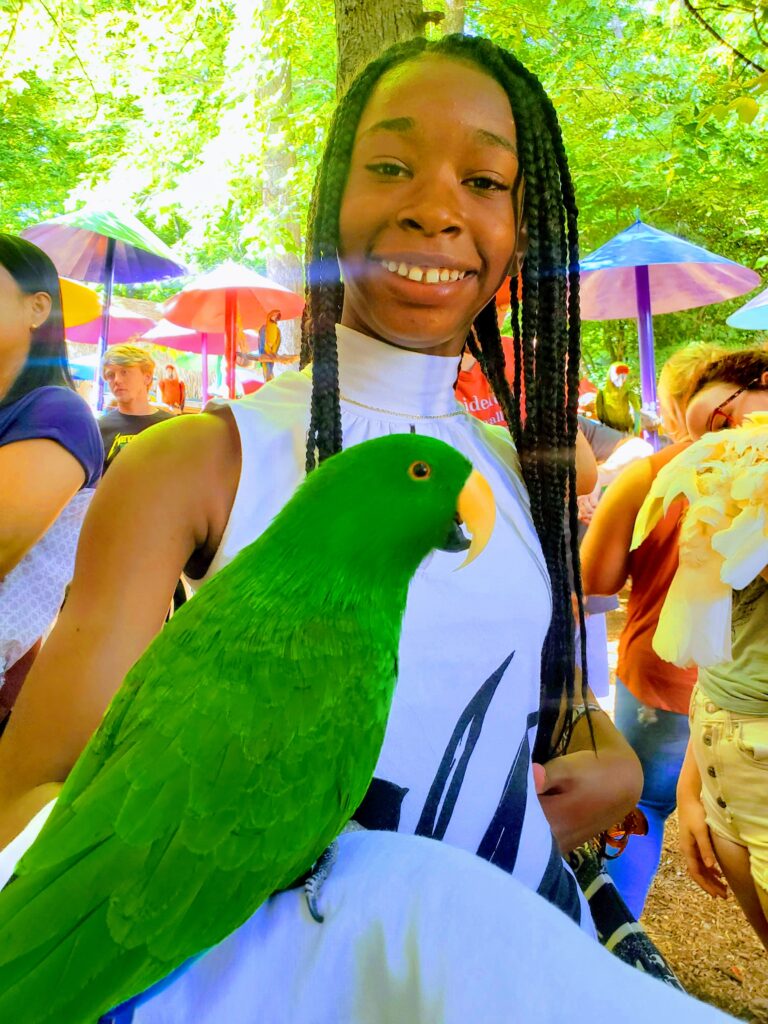 Girl and green bird at parrot mountain bird sanctuary.